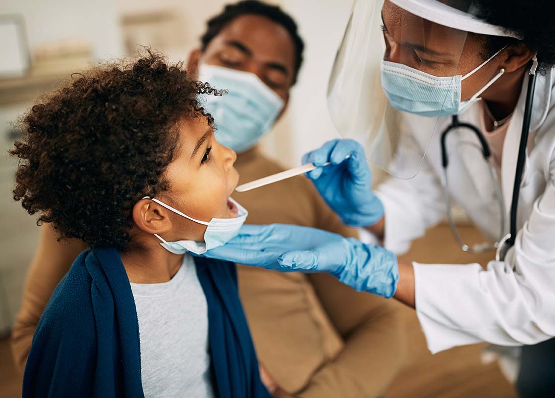 Family doctor inspecting child's mouth